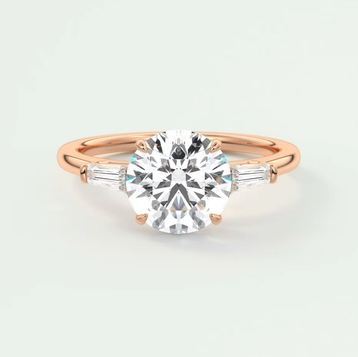 18-karat rose gold engagement ring with a round diamond and baguette diamonds.