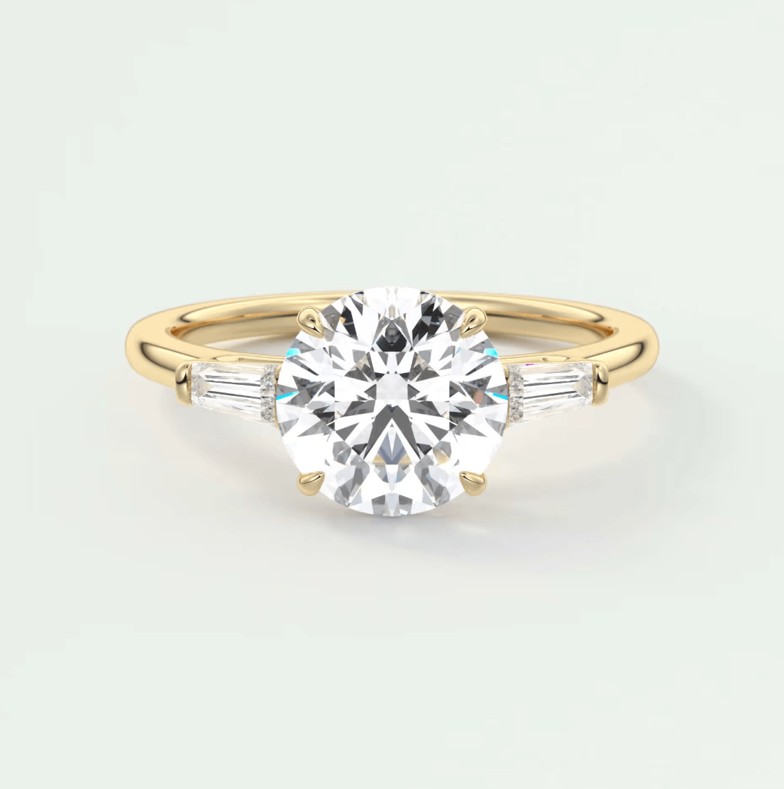 18-karat yellow gold engagement ring with a round diamond center and baguette diamonds on the band.