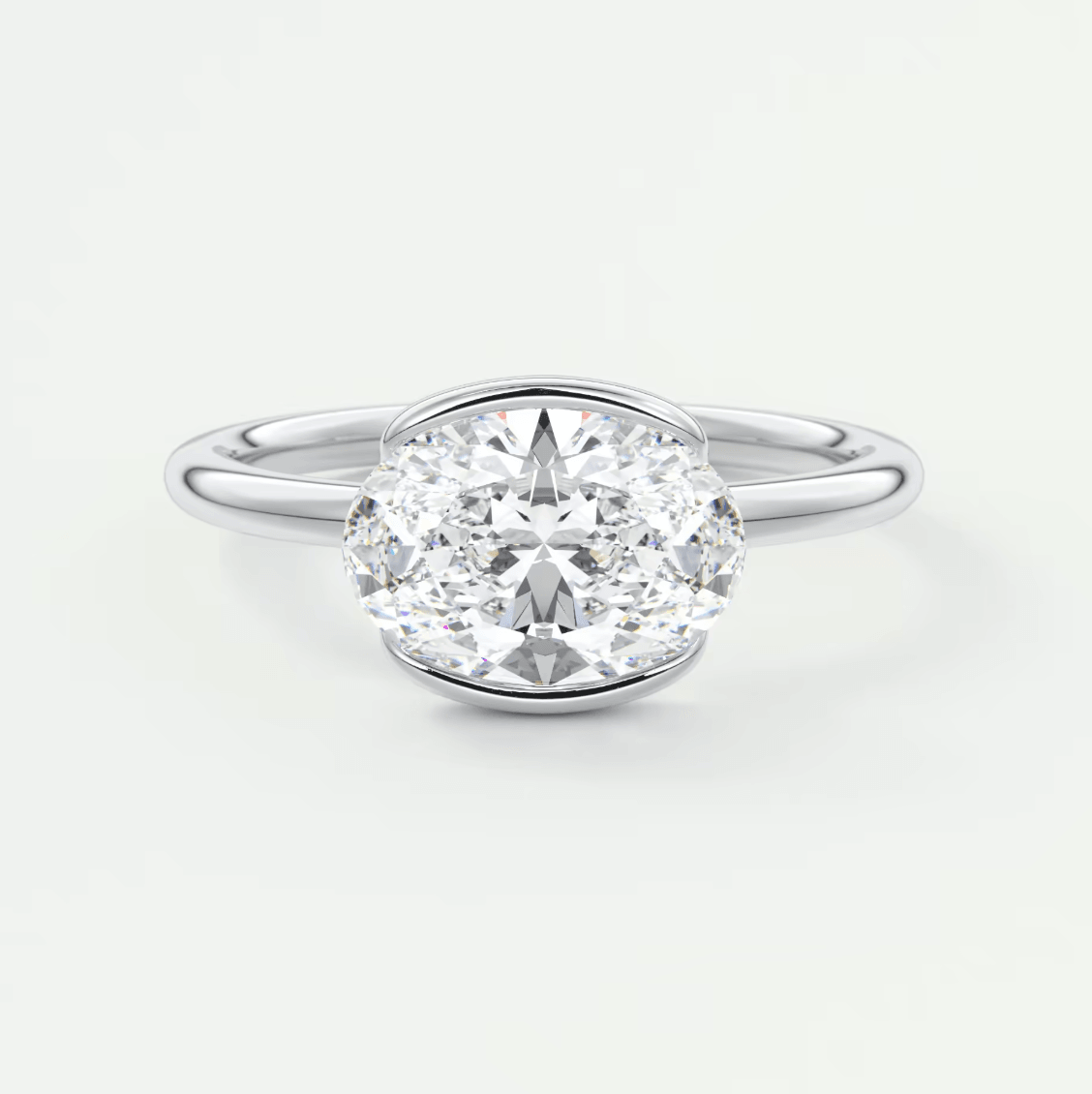 18-karat white gold oval diamond engagement ring with a bezel setting.