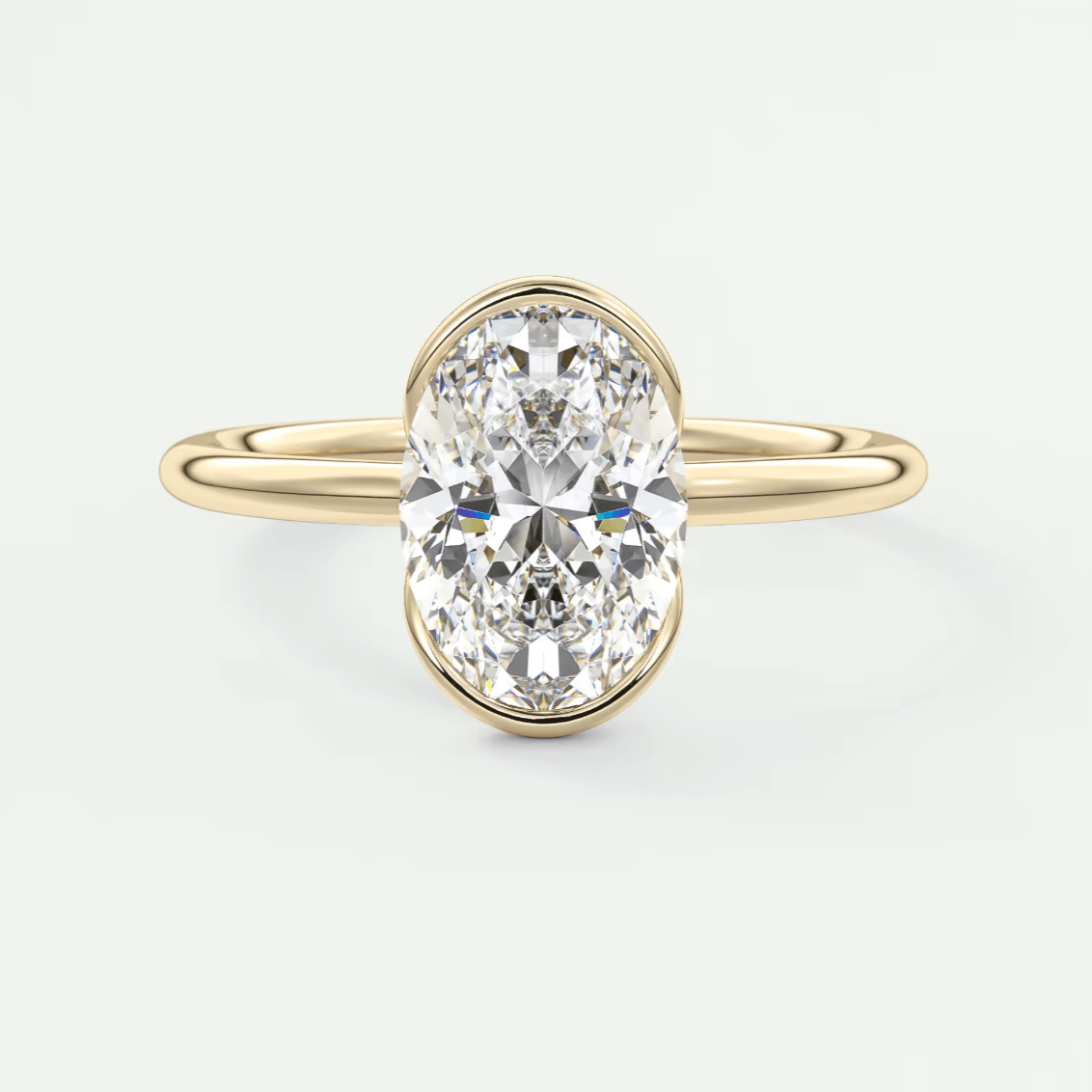 18k yellow gold oval diamond engagement ring with a bezel setting.