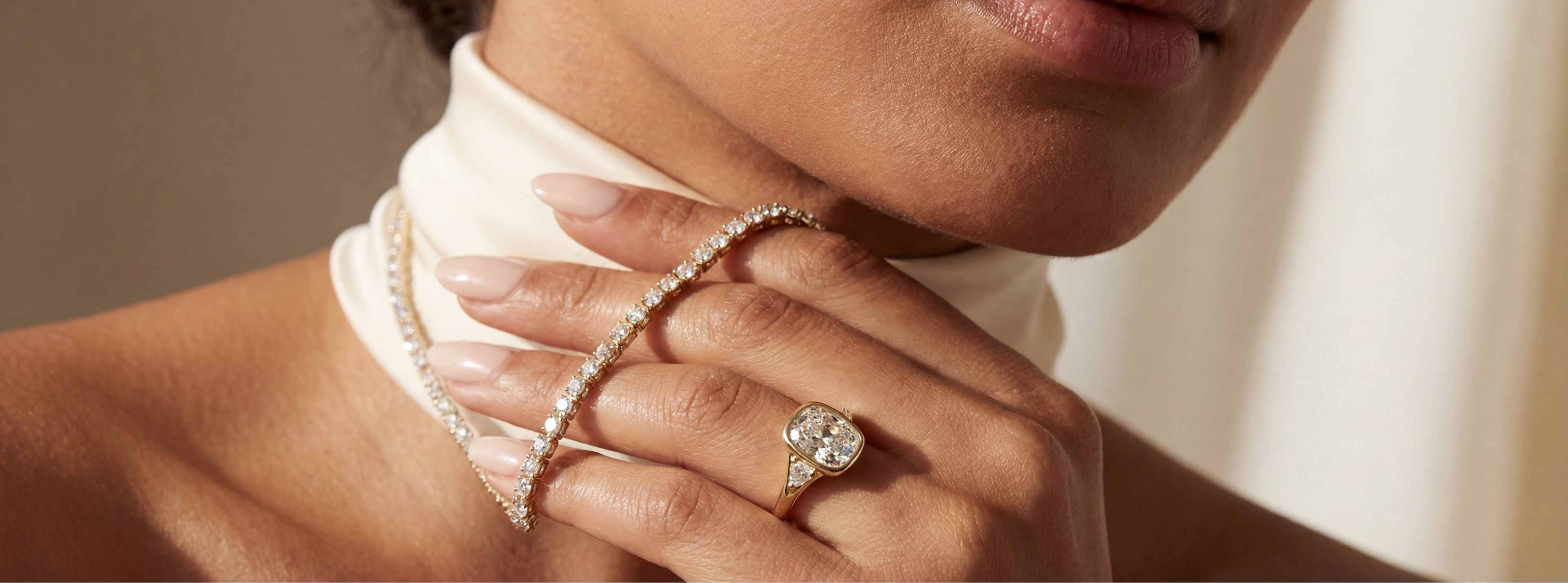 Close-up of a woman's hand wearing a diamond ring and bracelet against a neutral background