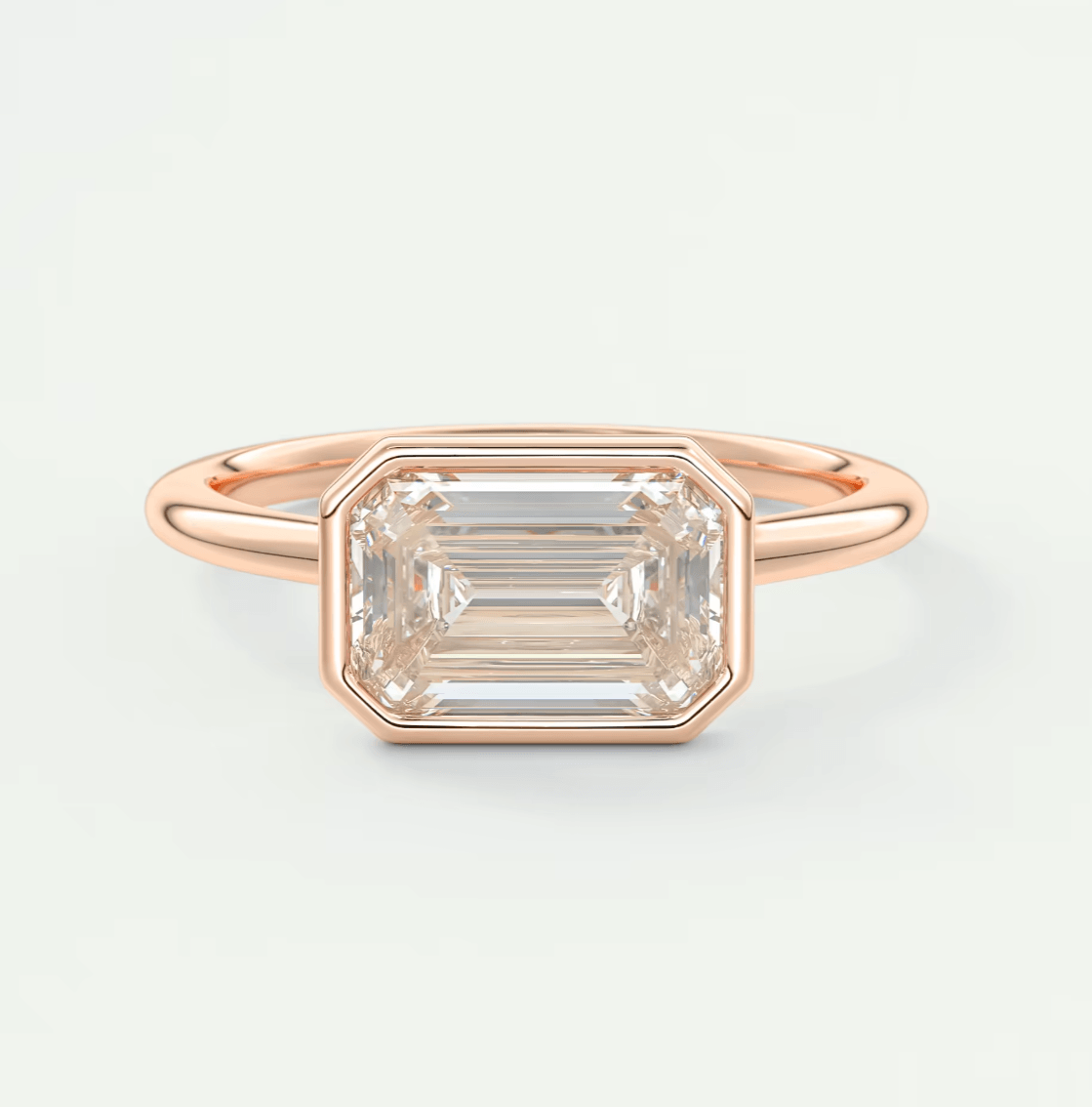 18-karat rose gold emerald-cut diamond ring with a bezel setting.