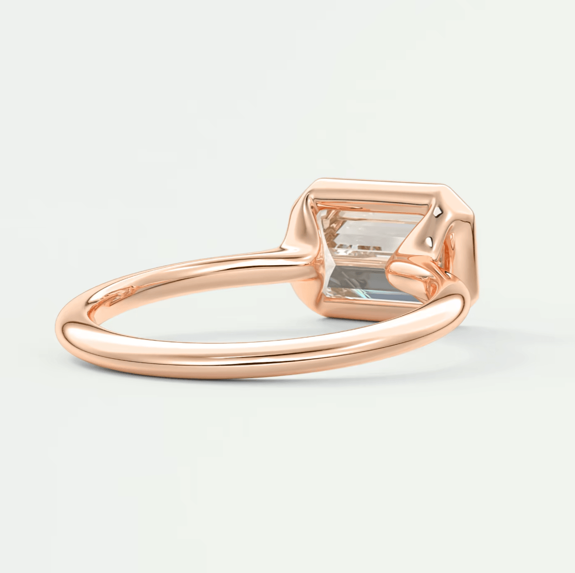 Rose gold emerald-cut gemstone ring with a princess cut diamond accent.