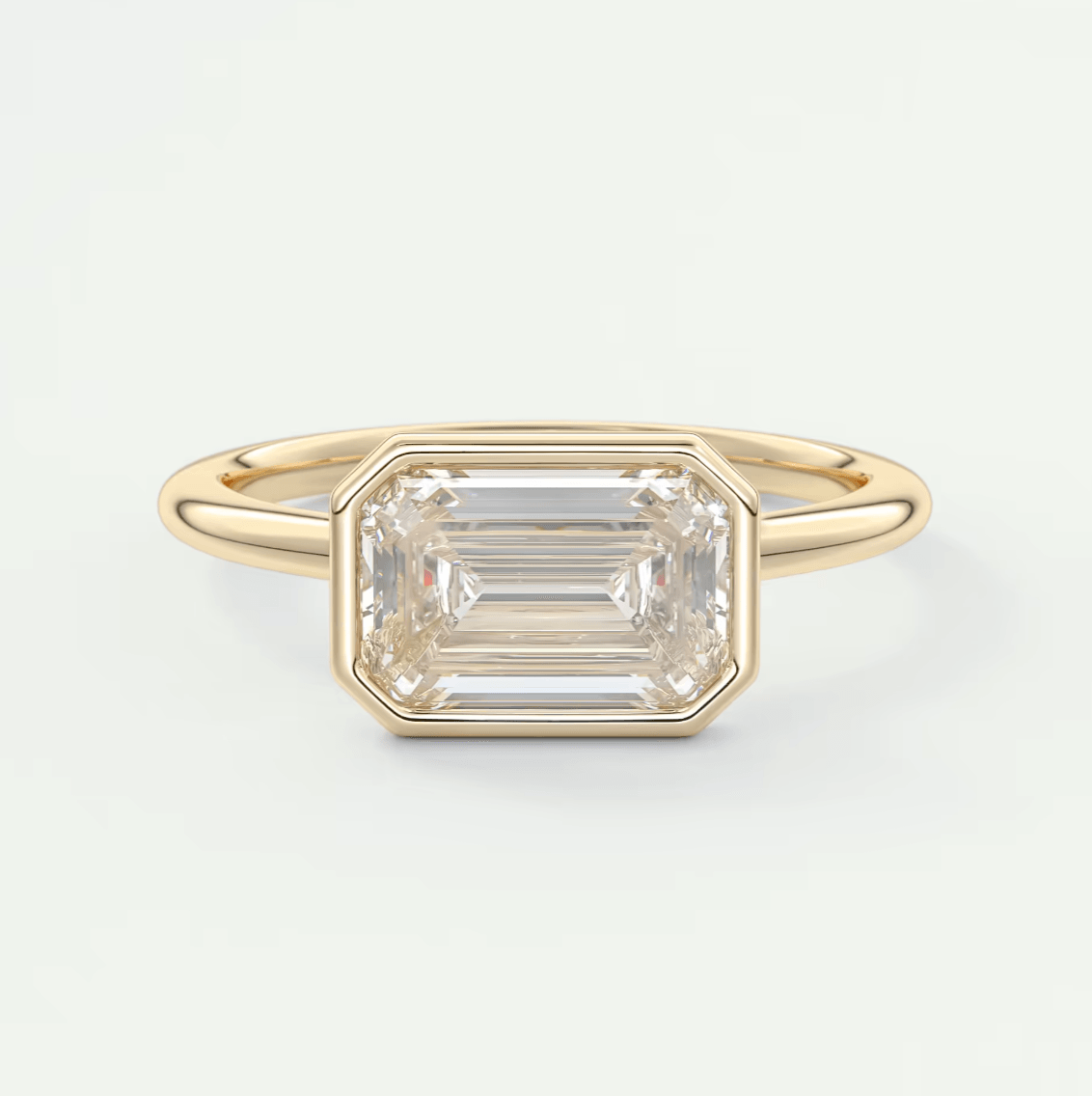 18-karat yellow gold emerald-cut diamond ring with a bezel setting.