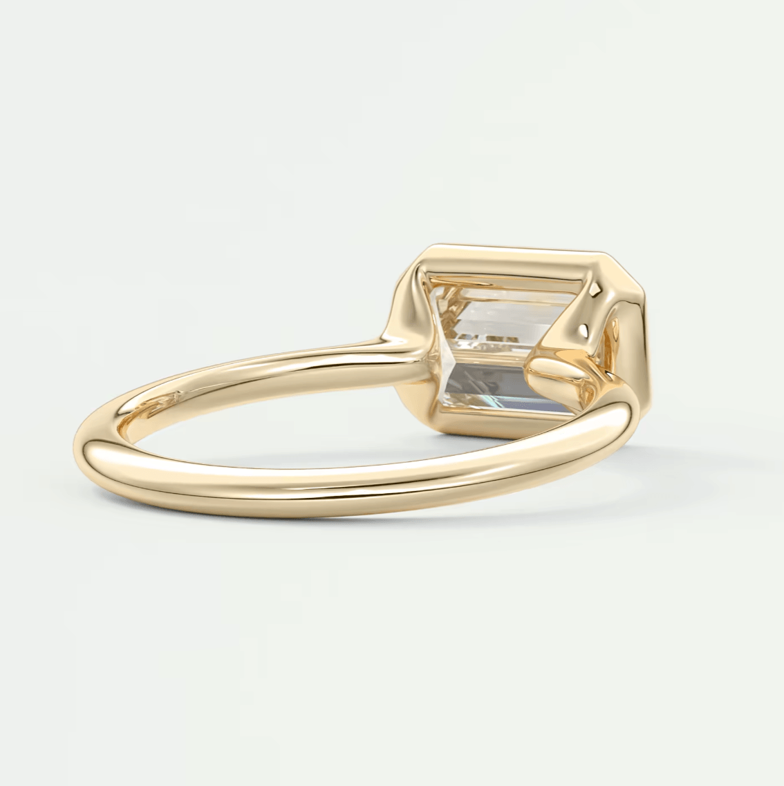 Gold emerald-cut gemstone ring with a clear stone set in a simple band.
