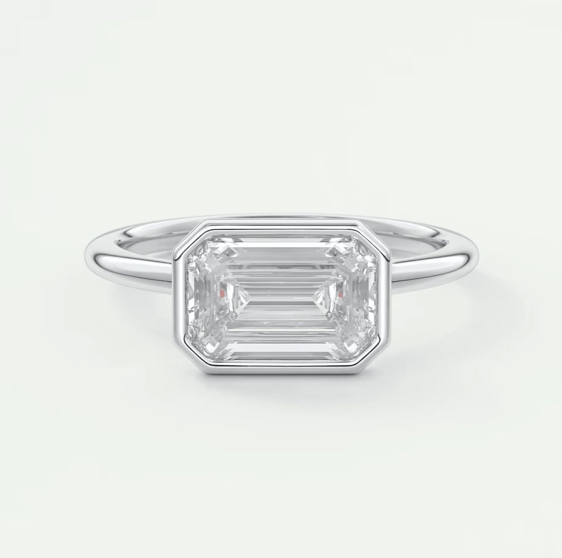 18k white gold emerald-cut diamond ring with a bezel setting.