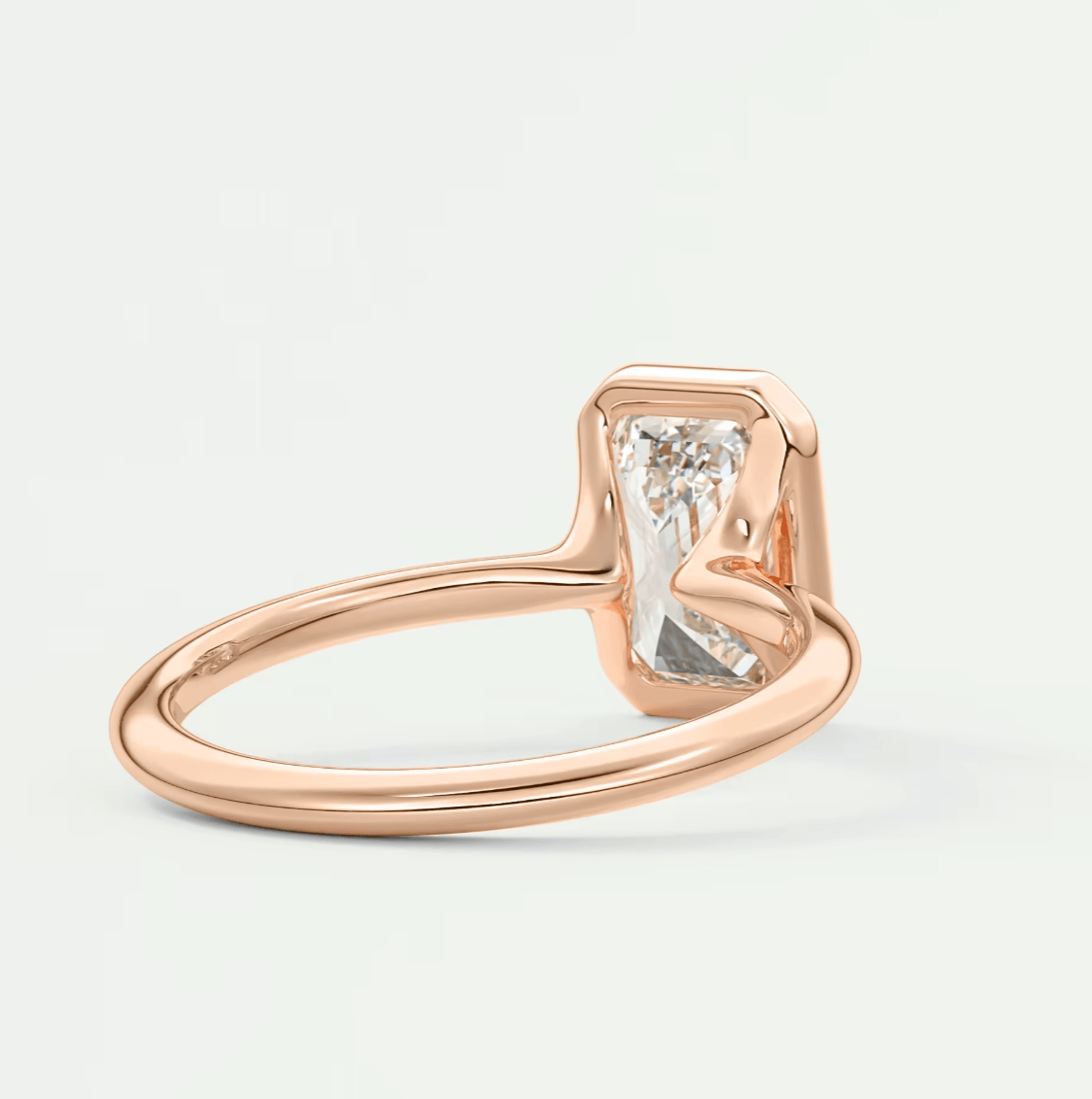 Rose gold engagement ring with a rectangular diamond center stone and curved band design.