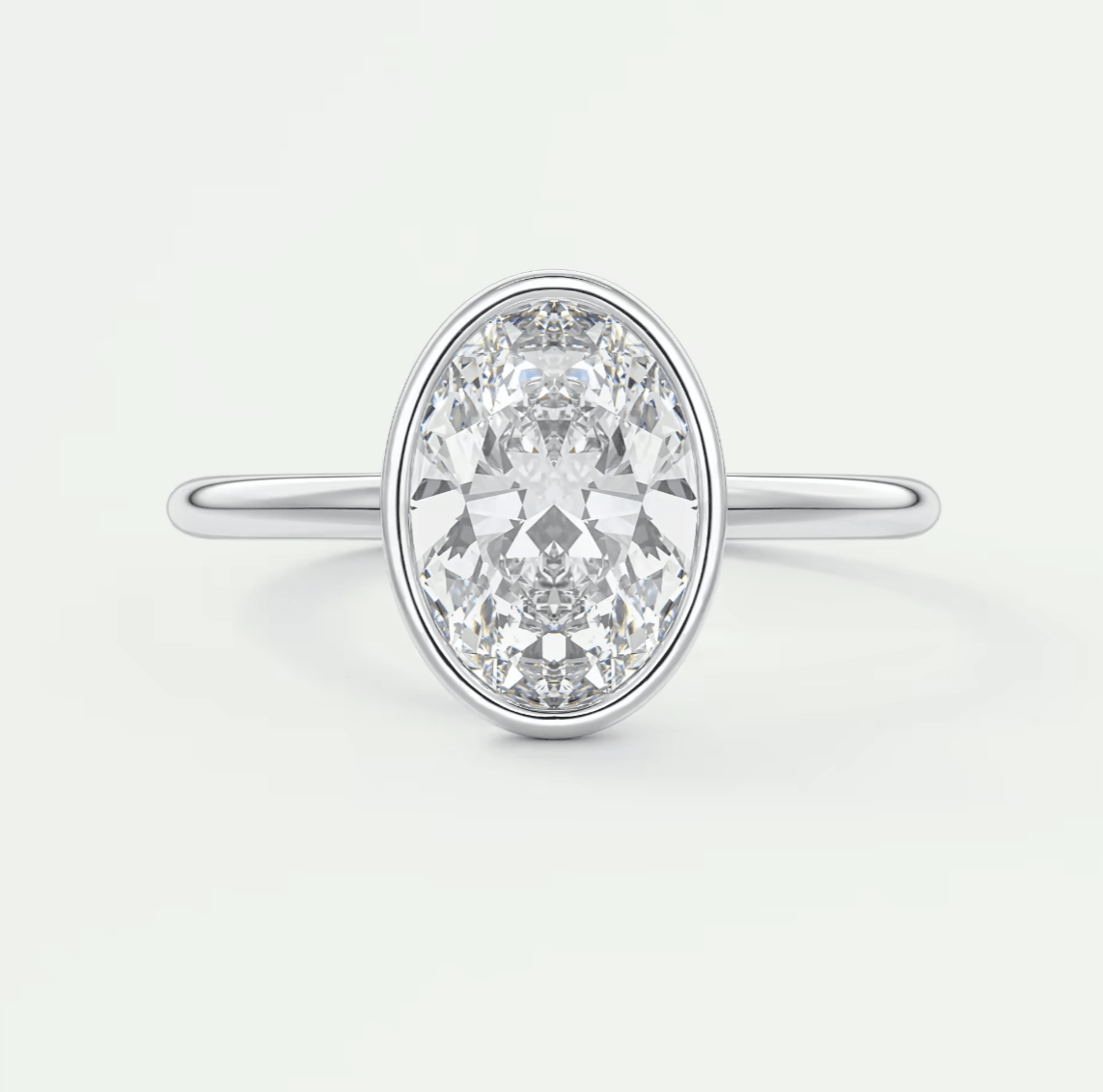 18k white gold oval diamond engagement ring with a bezel setting.