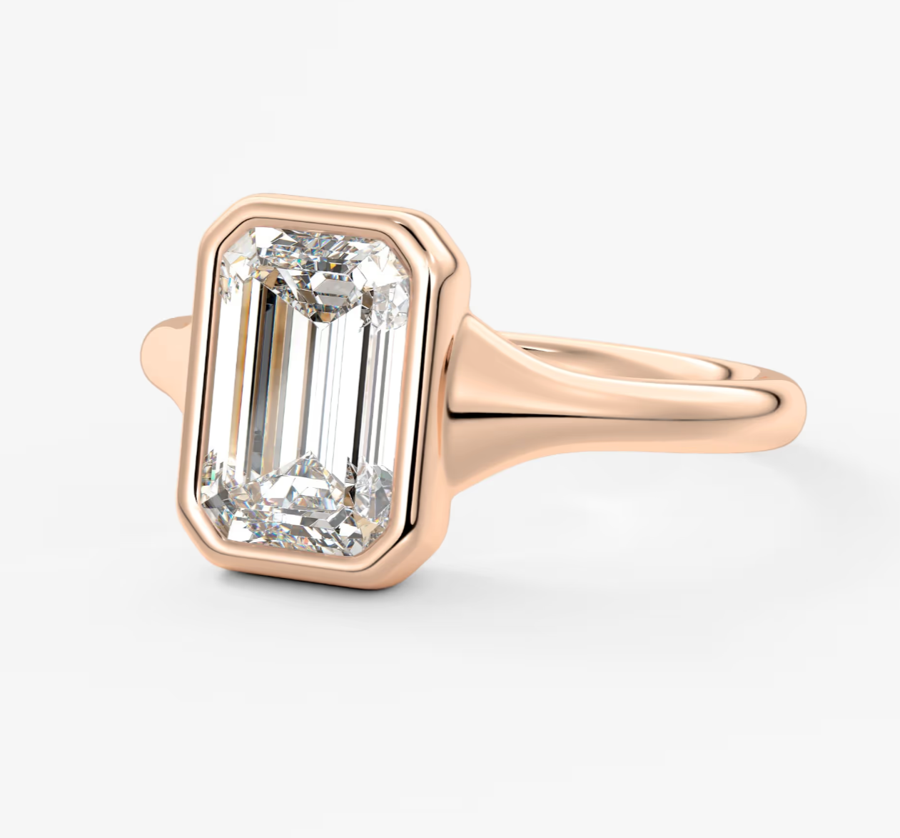 18k rose gold emerald-cut diamond ring with a bezel setting.