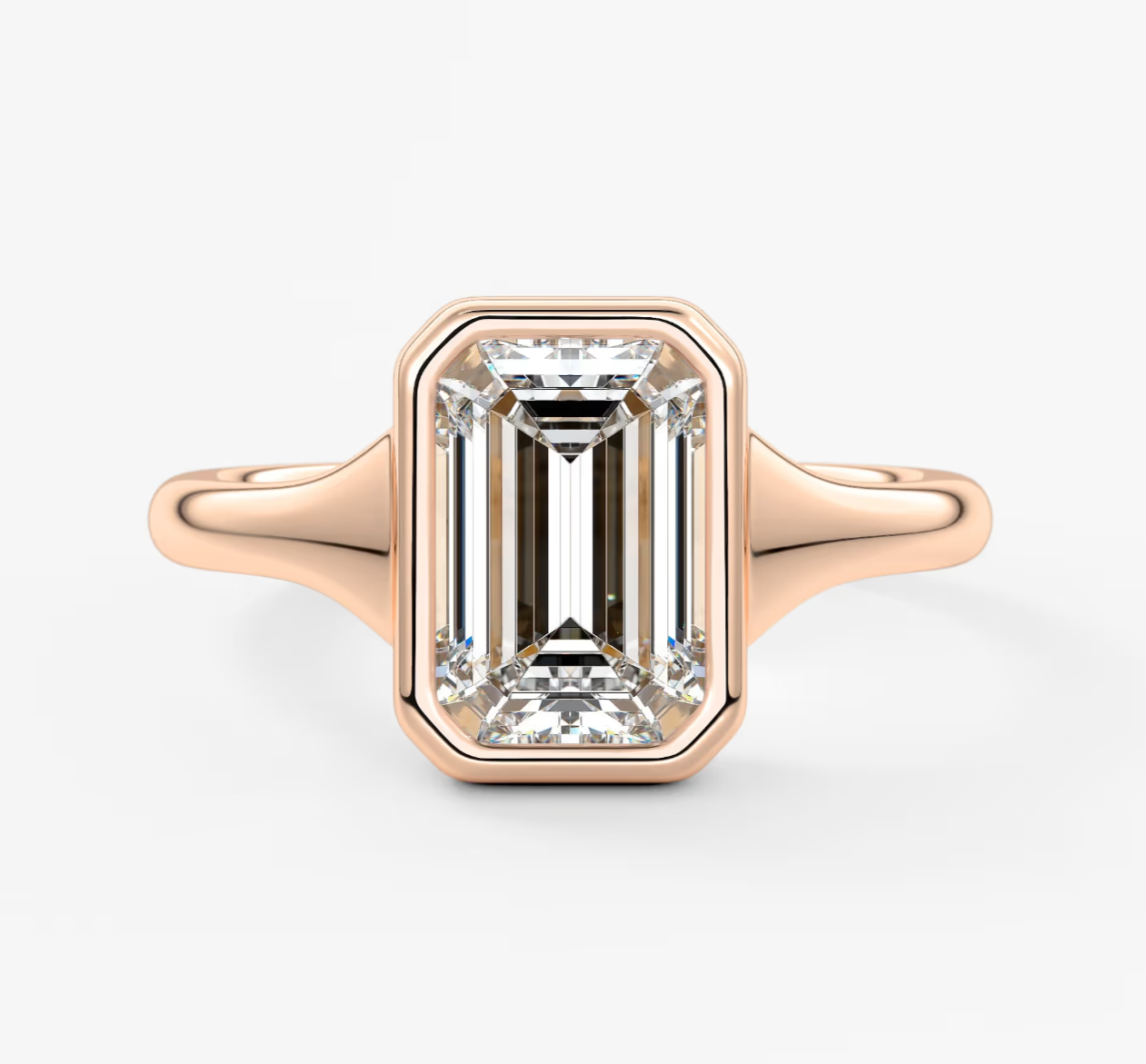 18k rose gold emerald cut diamond engagement ring with a bezel setting.