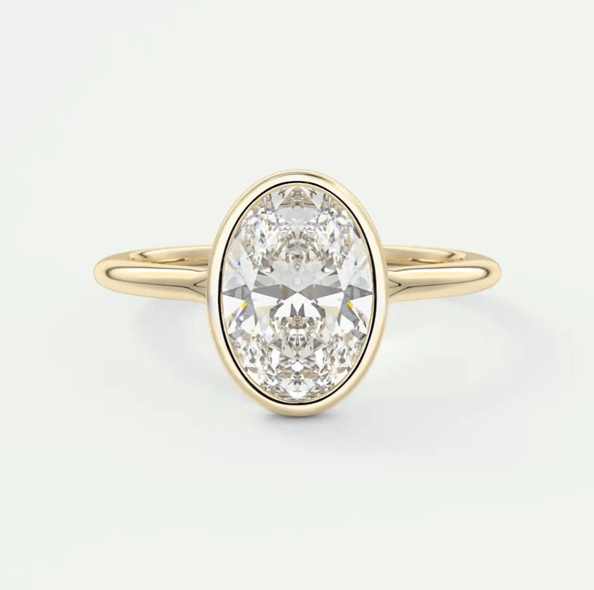 18k yellow gold oval diamond engagement ring with a bezel setting.