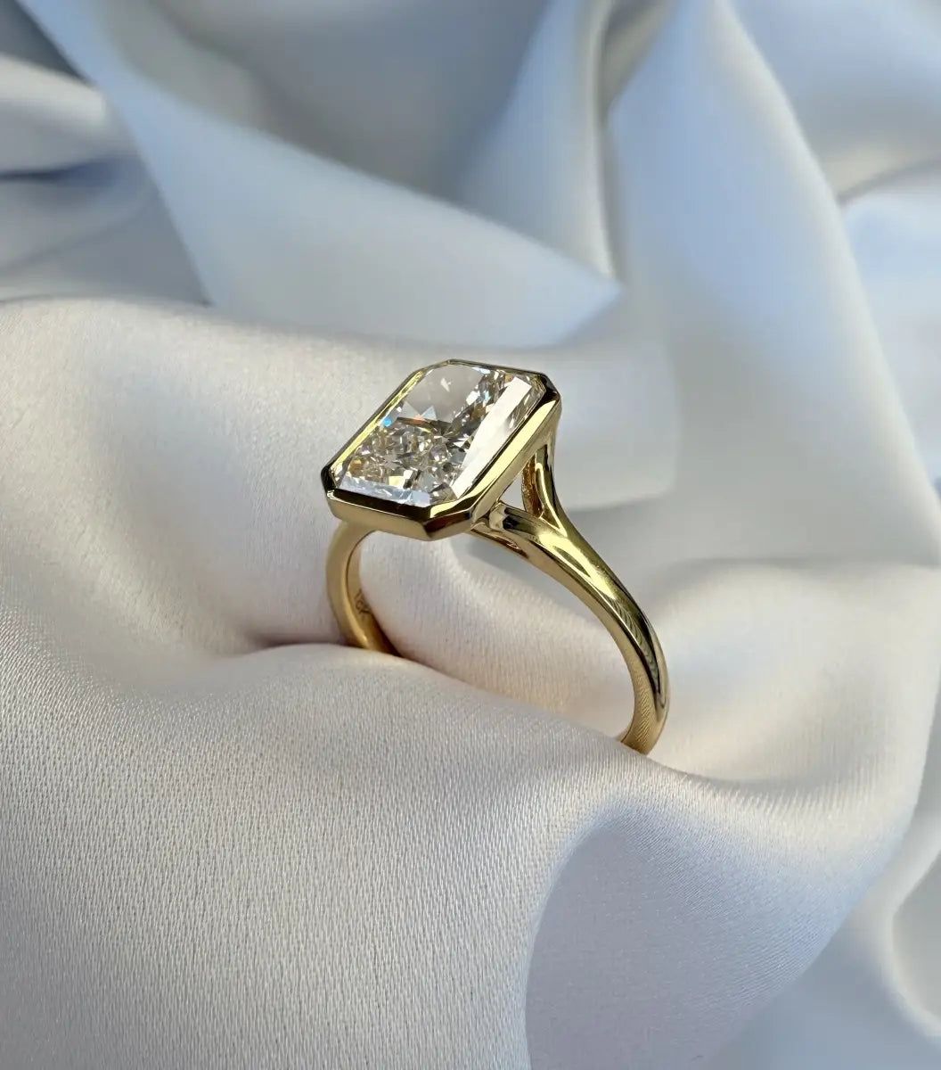 Gold ring with a large diamond on a white fabric background