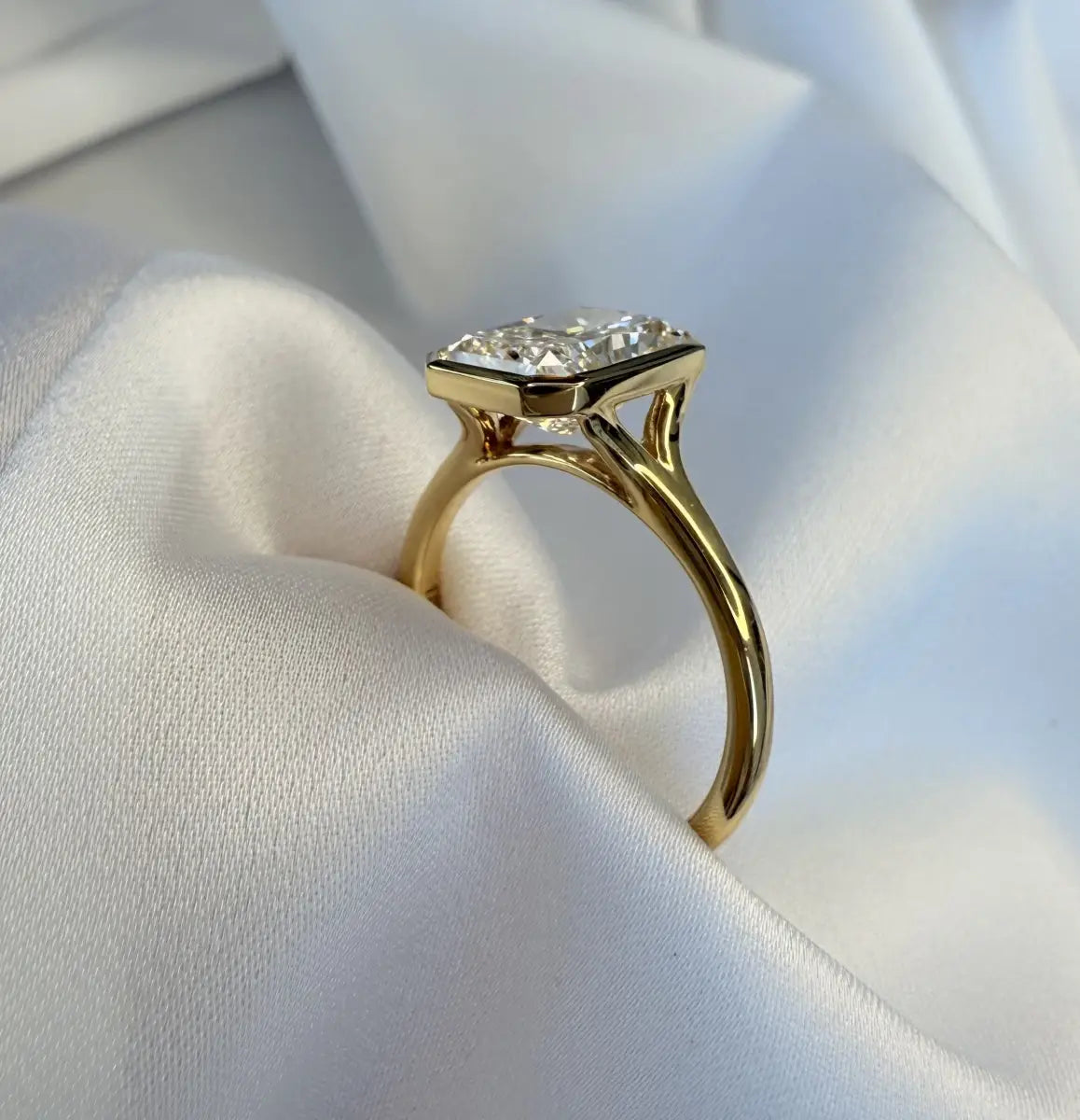 Gold ring with a diamond on a white fabric background
