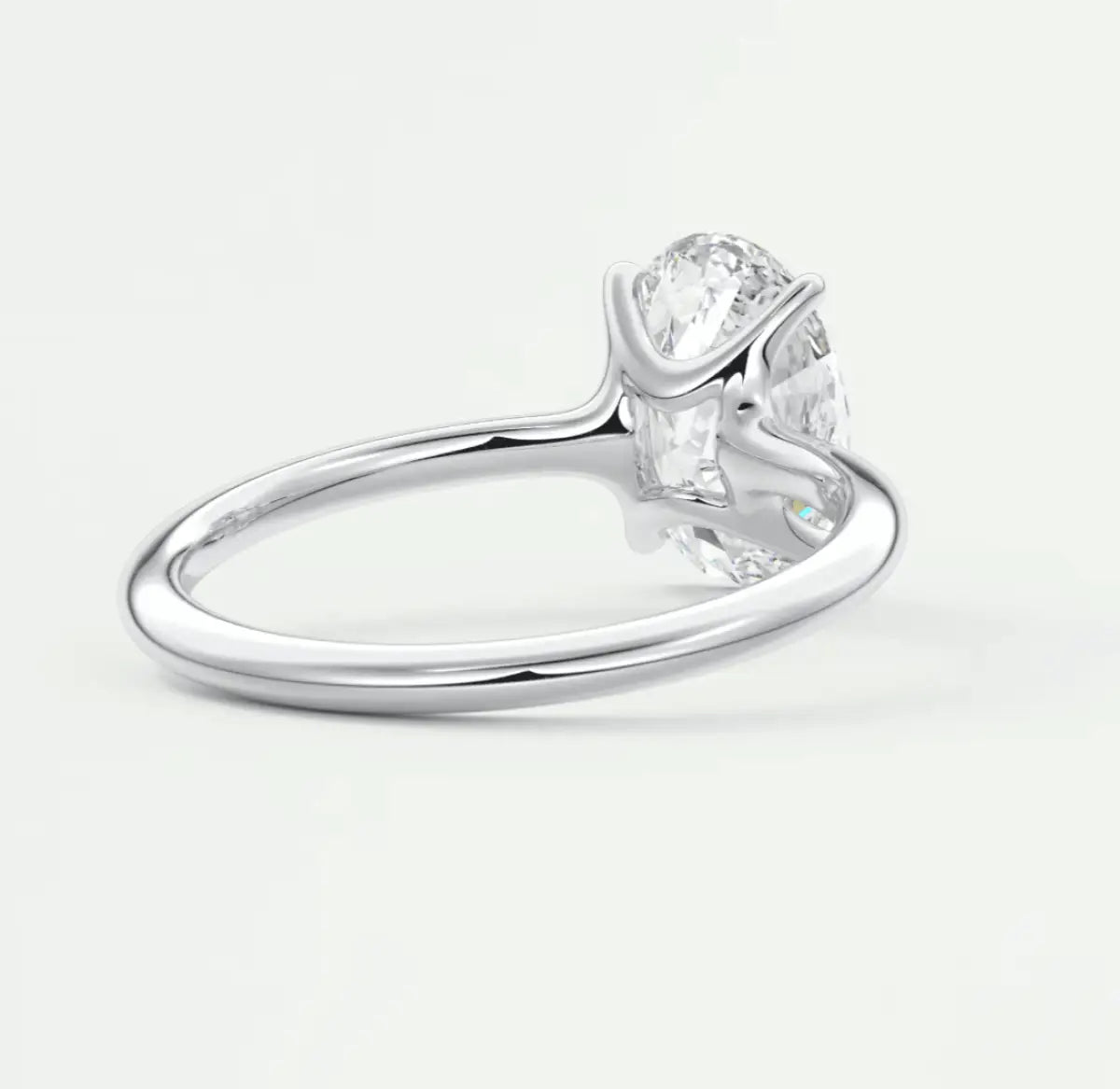 18k white gold diamond engagement ring with a pear-shaped center stone and two smaller stones on either side.