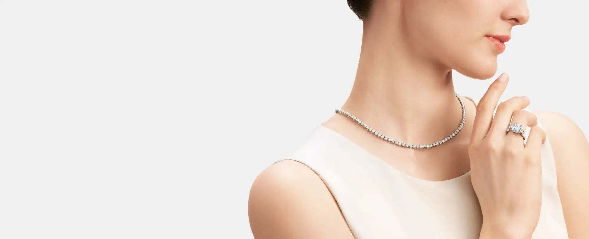 Woman wearing a necklace and ring on a plain background