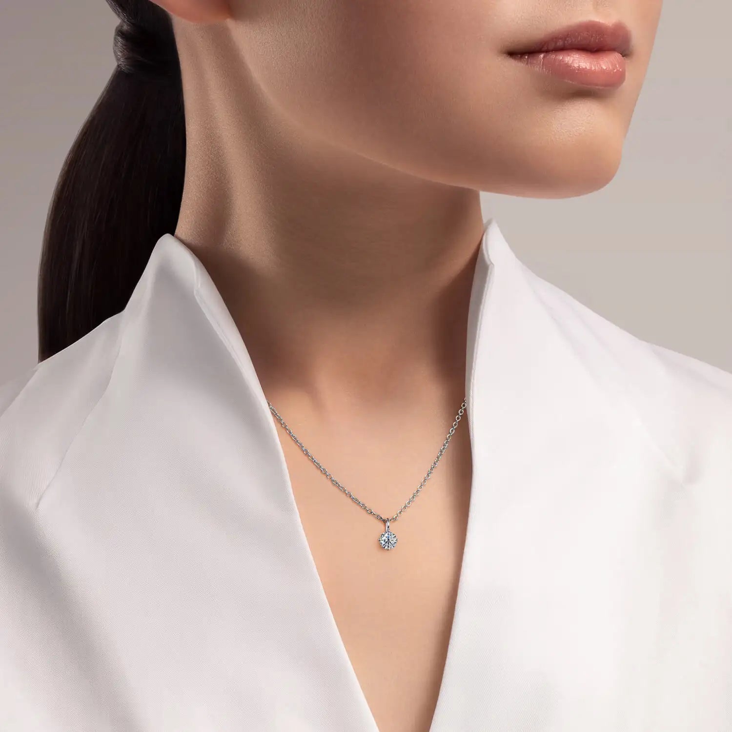A delicate silver chain necklace featuring a single, sparkling diamond pendant.