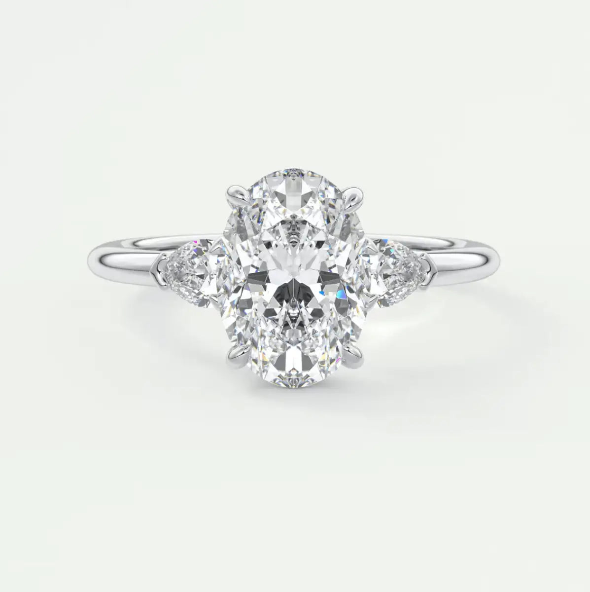 18k white gold diamond engagement ring with an oval-cut center stone and pear-shaped side stones.