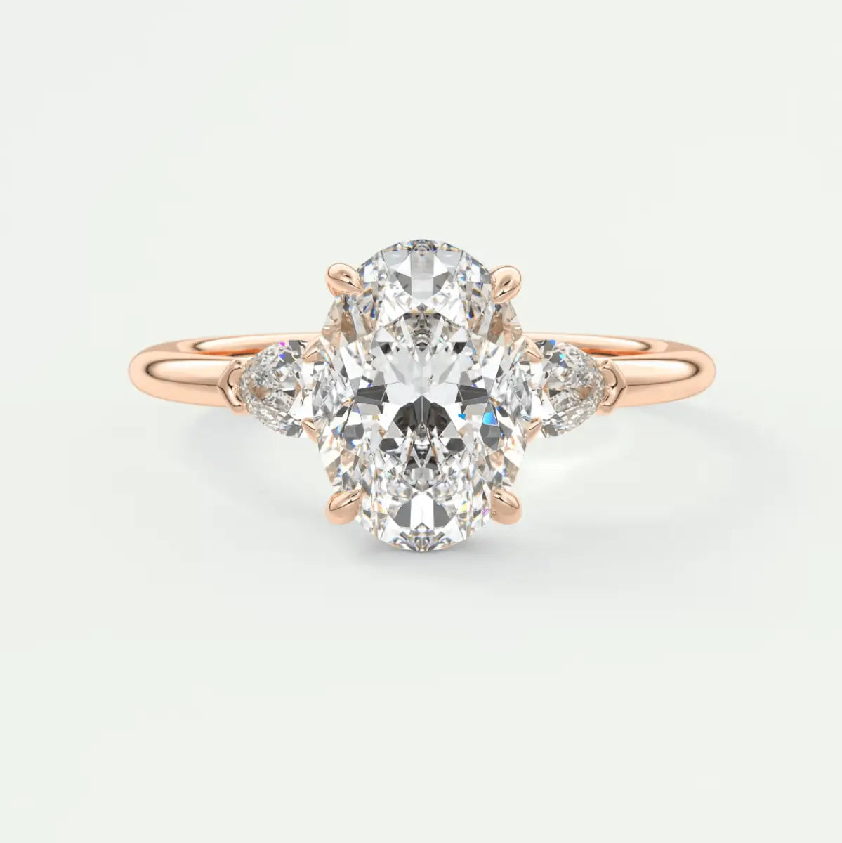 18k rose gold diamond engagement ring with an oval center stone and pear-shaped side stones.