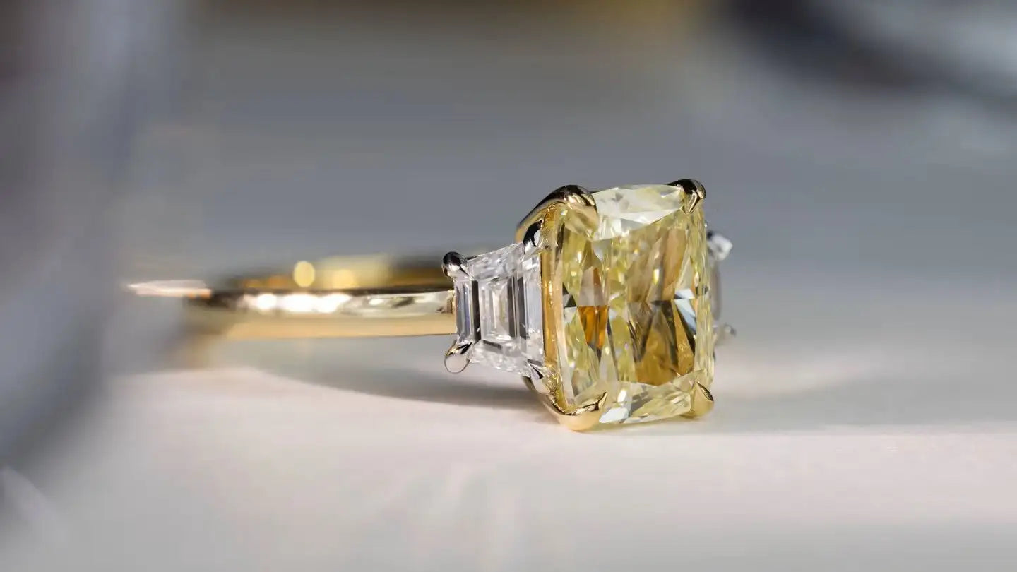 Gold ring with a yellow diamond on a neutral background