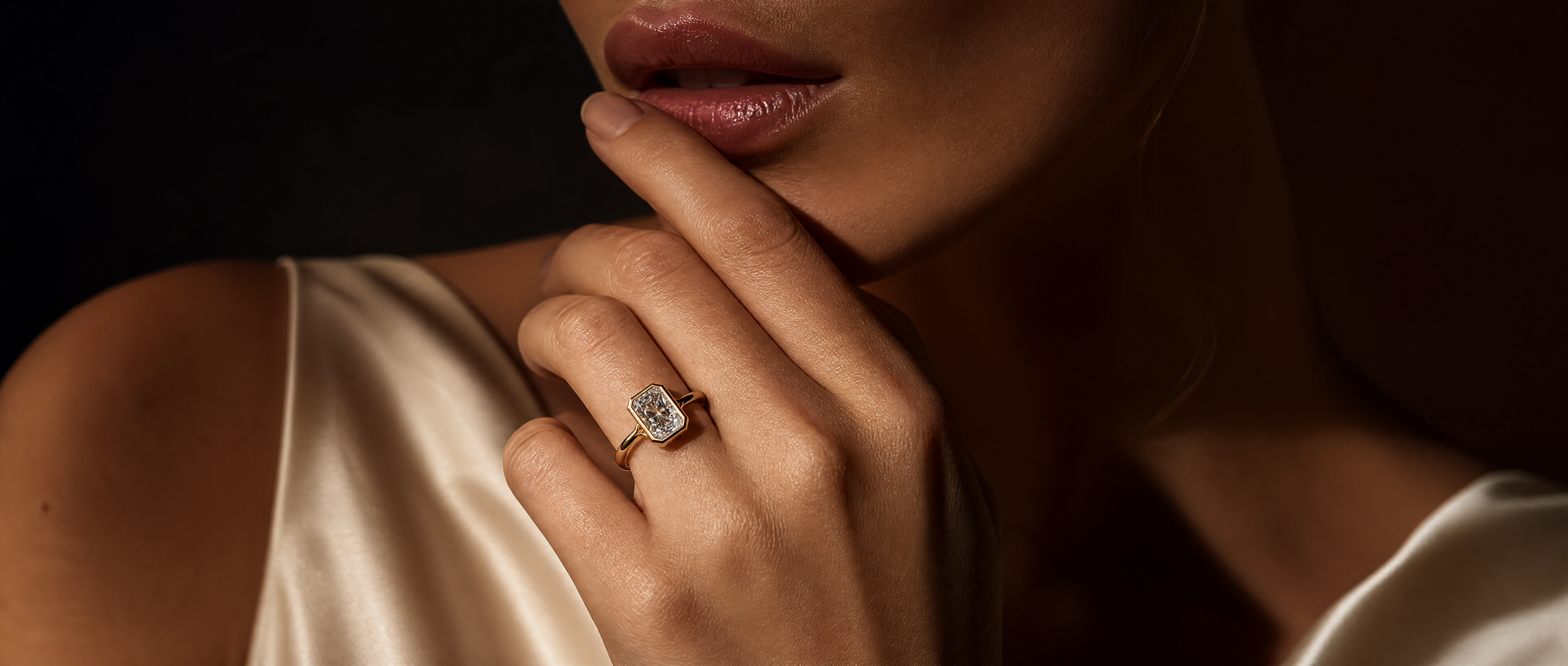 Close-up of a hand with a diamond ring on a dark background