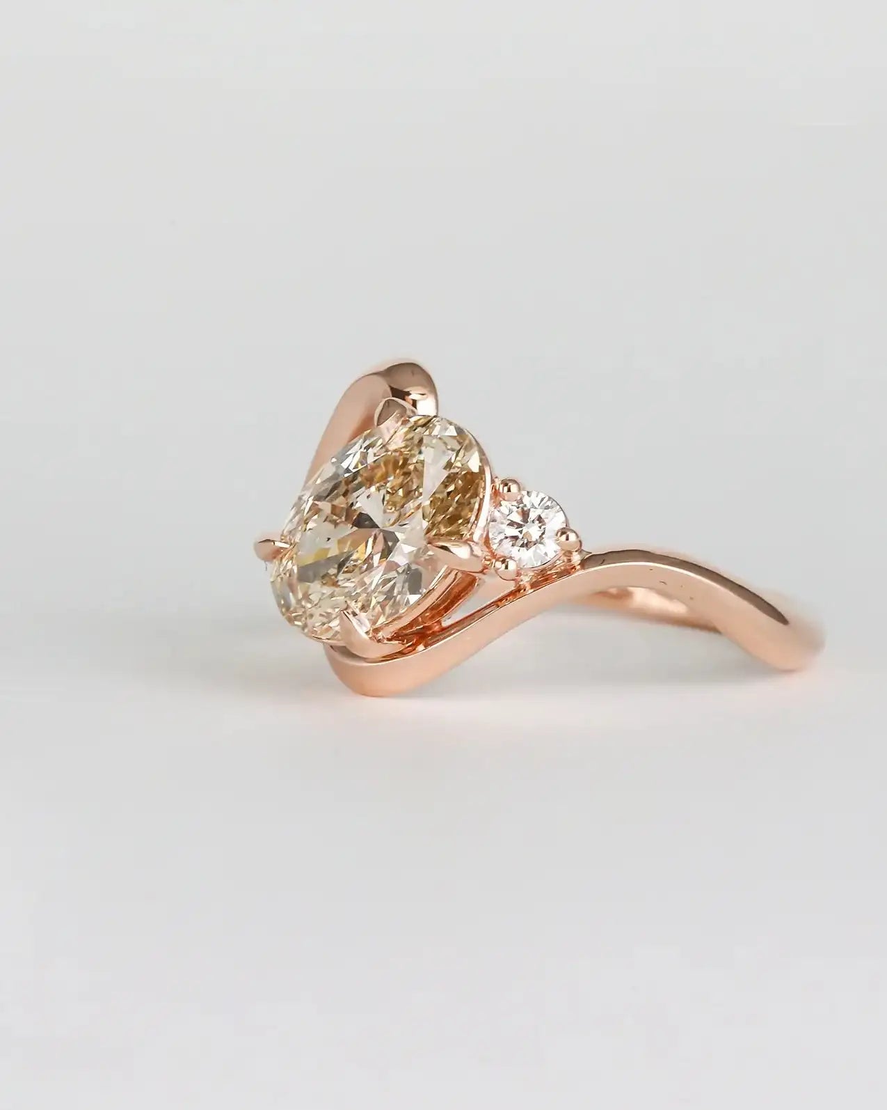 Rose gold ring with a pear-shaped diamond on a light gray background