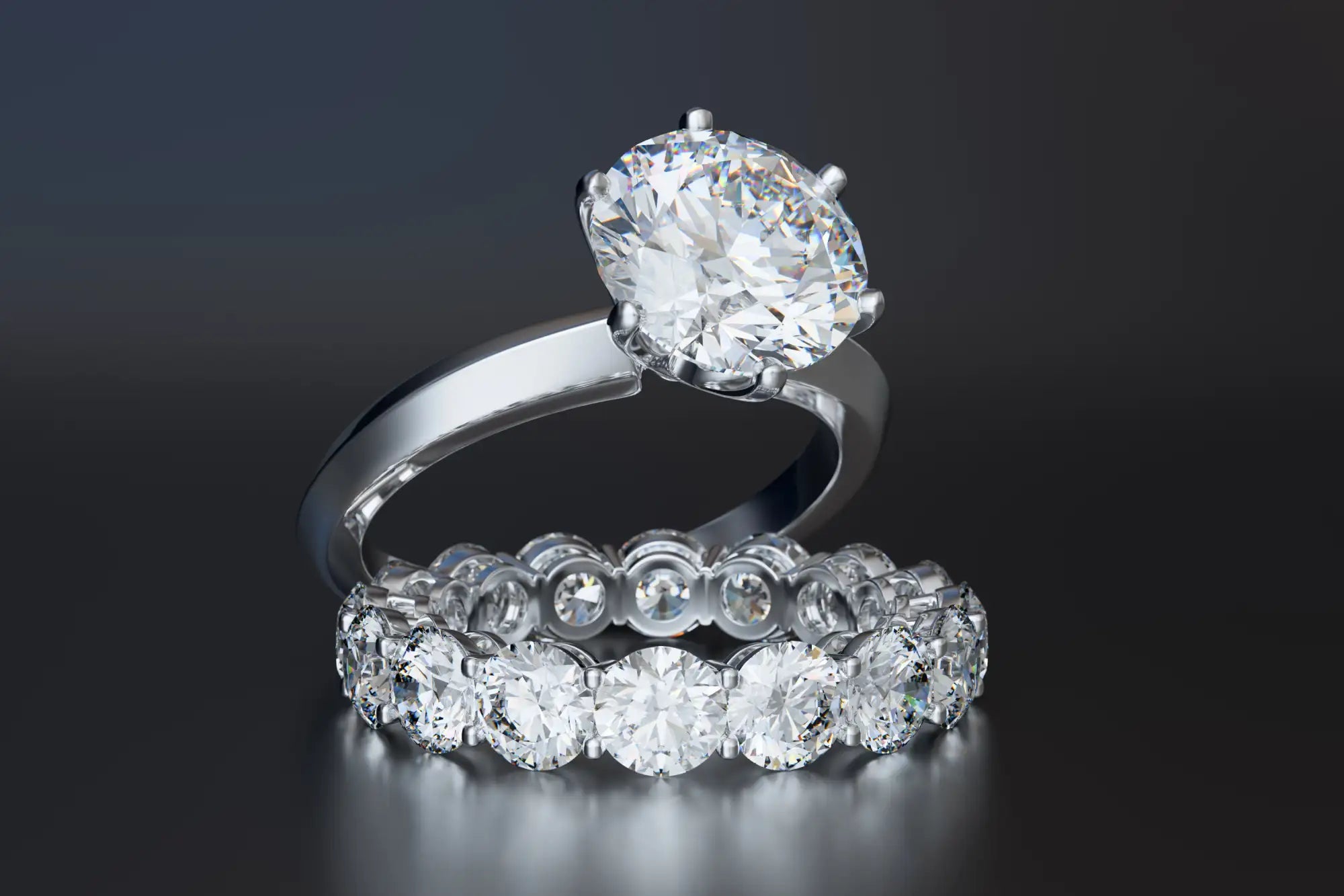 A sleek platinum engagement ring featuring a prominent round-cut diamond held by six prongs, displayed alongside an eternity band adorned with evenly spaced brilliant-cut diamonds.