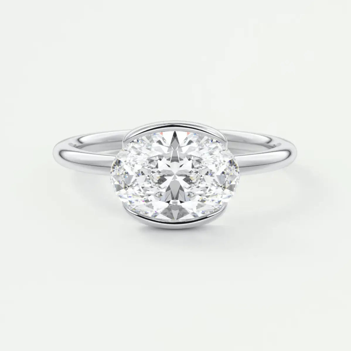 18-karat white gold oval diamond engagement ring with a bezel setting.