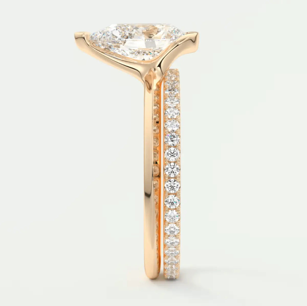 18k rose gold diamond engagement ring with a pear-shaped center stone and channel-set diamonds on the band.