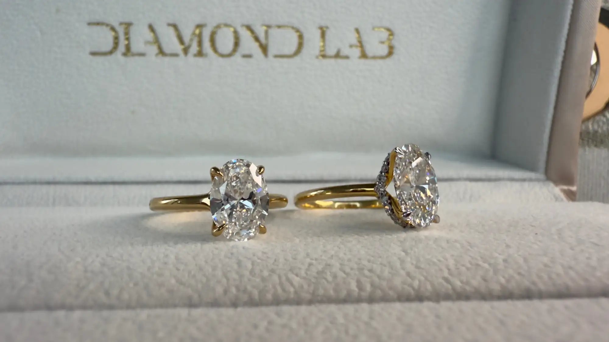 Two diamond rings on a cushioned surface with 'Diamond Lab' branding.