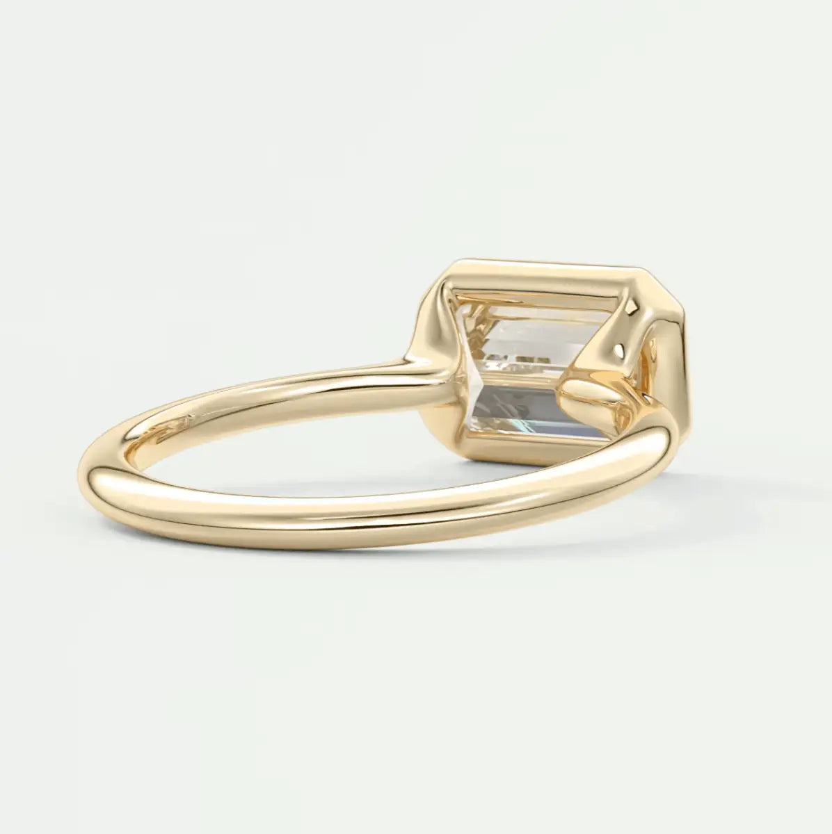 Gold emerald-cut gemstone ring with a clear stone set in a simple band.