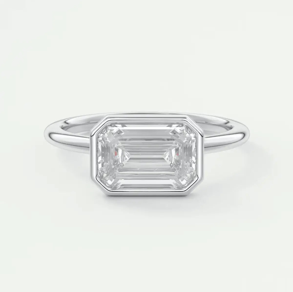 18k white gold emerald-cut diamond ring with a bezel setting.