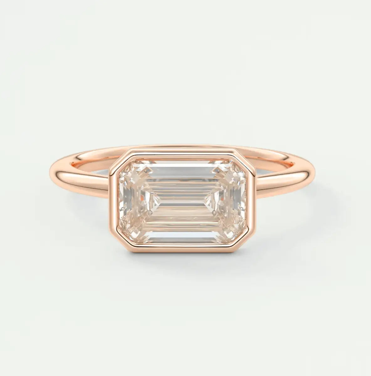 18-karat rose gold emerald-cut diamond ring with a bezel setting.