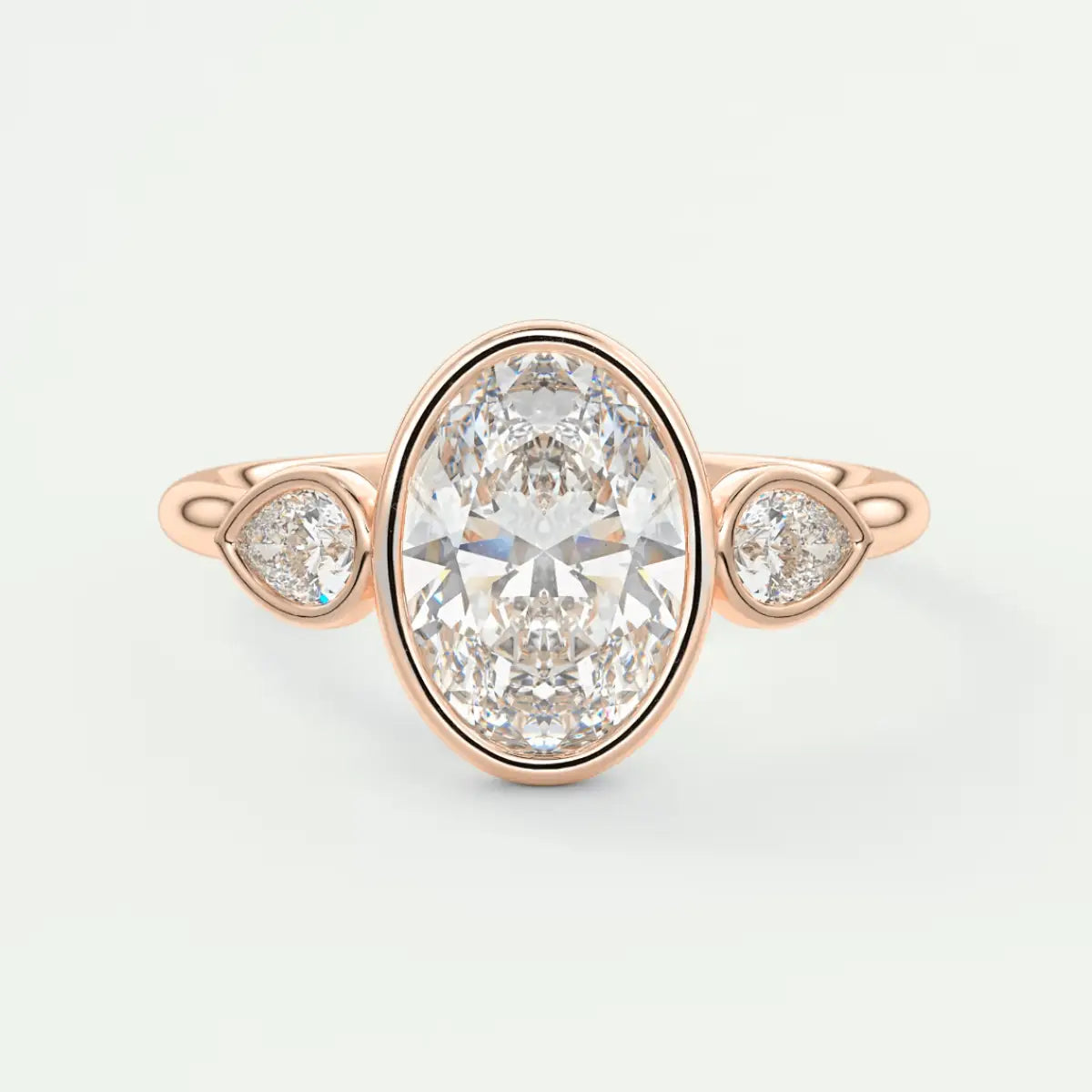 Rose gold diamond engagement ring with three pear-shaped diamonds set in a bezel setting.
