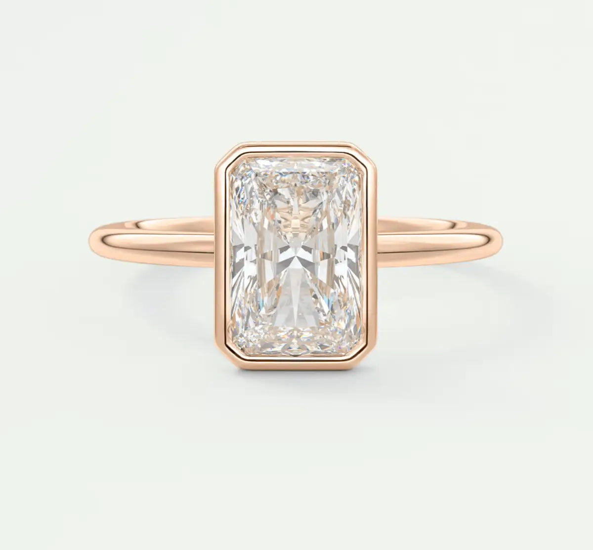 18k rose gold emerald cut diamond ring with a bezel setting.