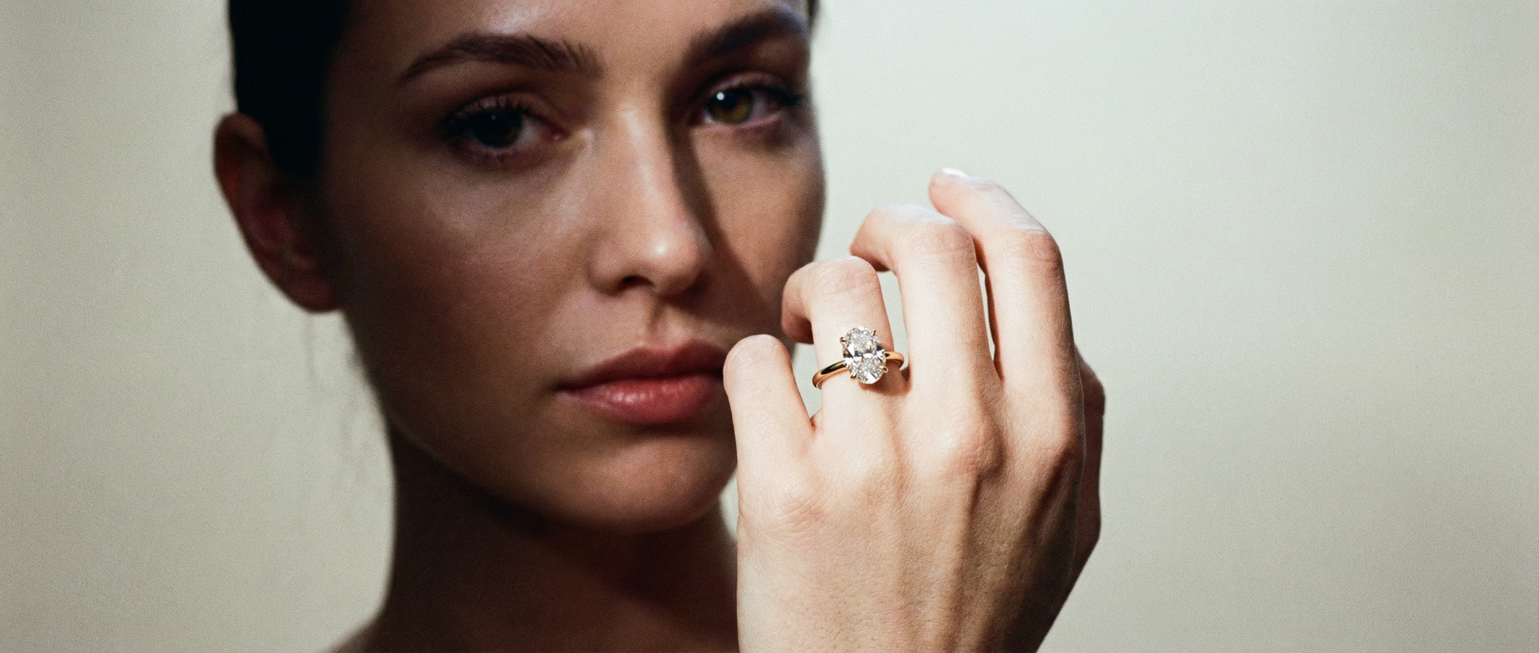 Woman wearing a diamond ring on a neutral background