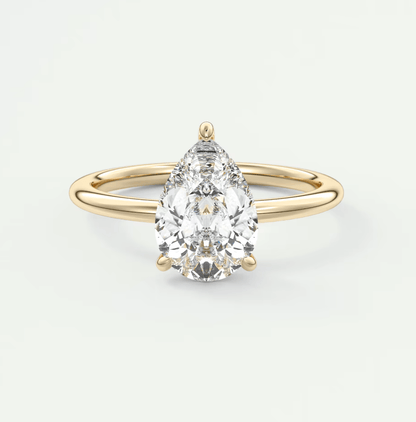 Pear-shaped diamond engagement ring with gold band and prong setting.