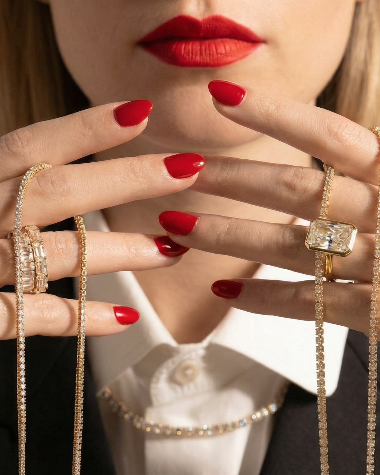 Close-up of a woman's hands with red nail polish wearing multiple rings.