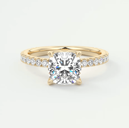 18-karat yellow gold engagement ring with a cushion-cut diamond and pavé set diamonds on the band.