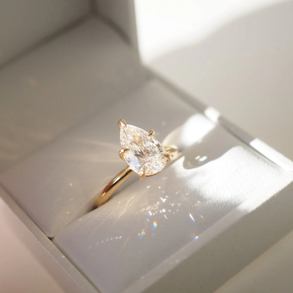 Gold ring with a pear-shaped diamond in a white box