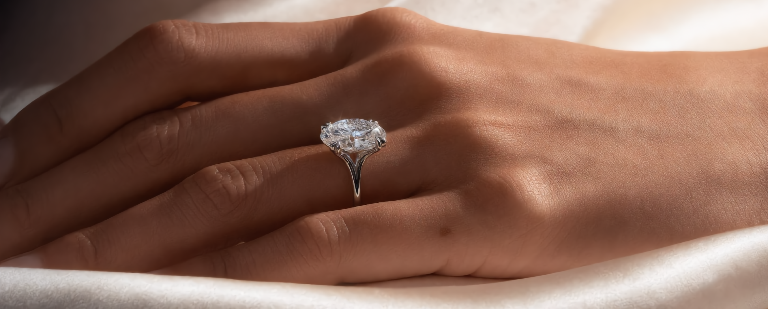 Hand wearing a diamond ring on a soft fabric background