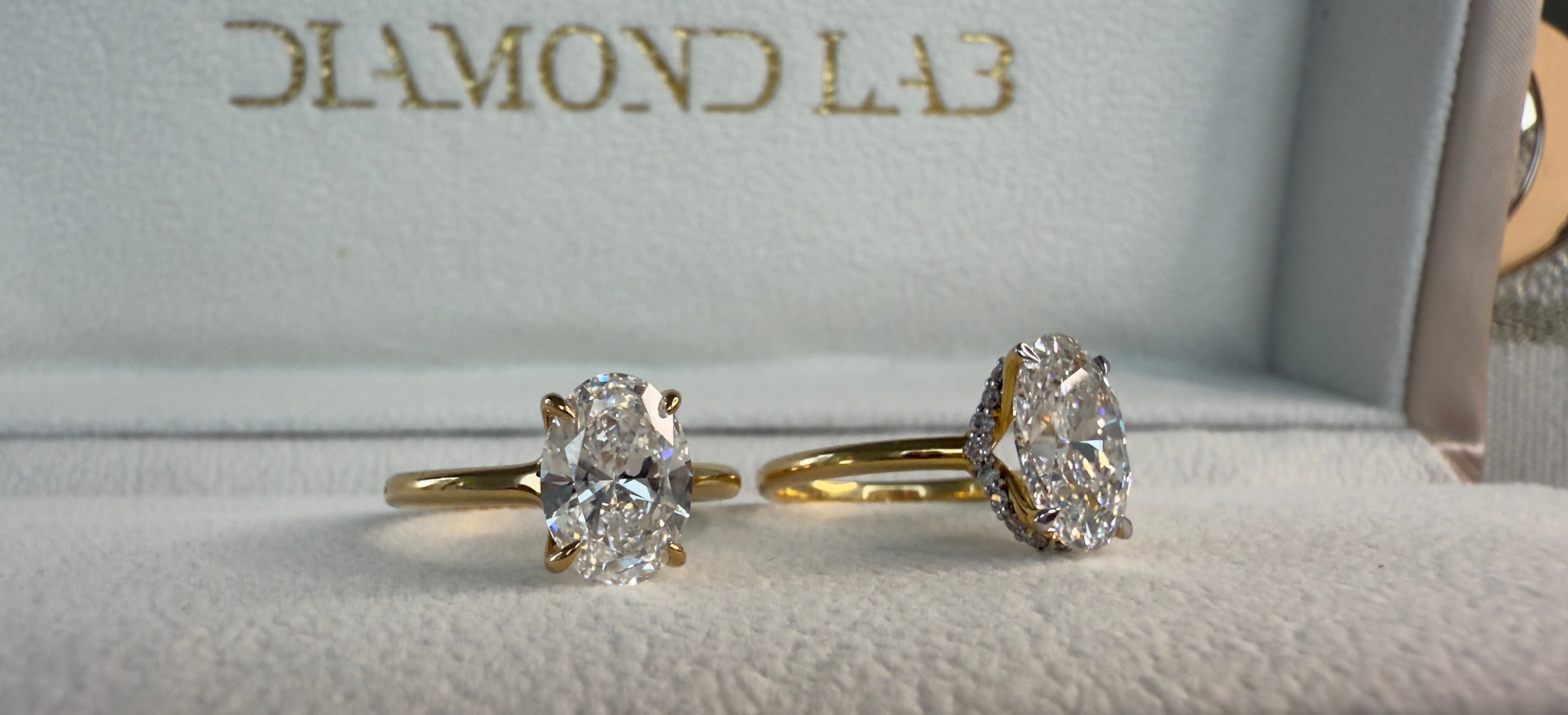 Two diamond rings on a cushioned surface with 'Diamond Lab' branding.