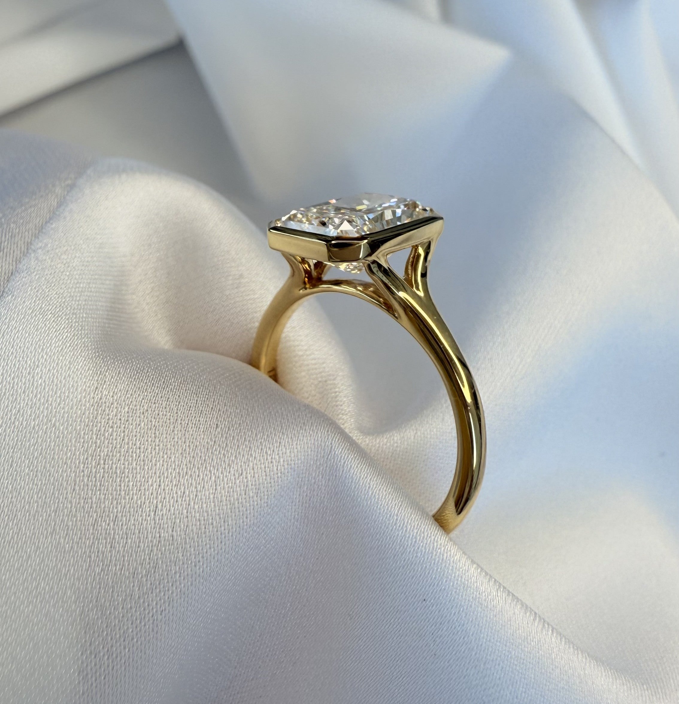 Gold ring with a diamond on a white fabric background