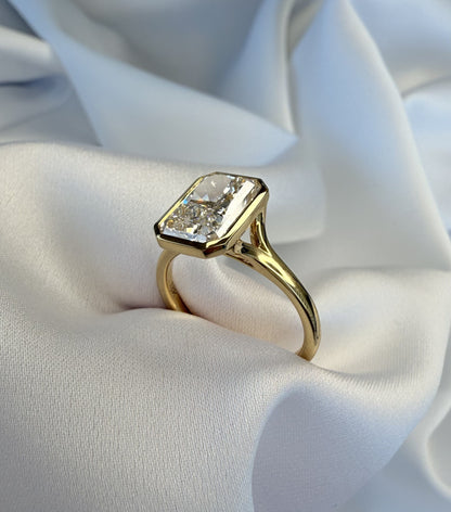 Gold ring with a large diamond on a white fabric background
