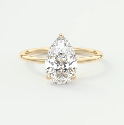 Pear-shaped diamond engagement ring with gold band, featuring a large central stone and smaller accent diamonds.