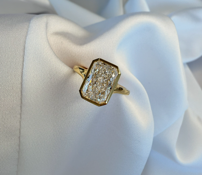 Gold ring with a diamond on a white fabric background