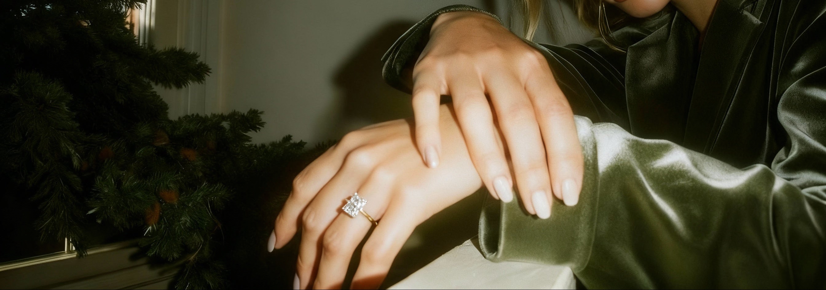 Woman wearing a ring in a softly lit room with a plant in the background