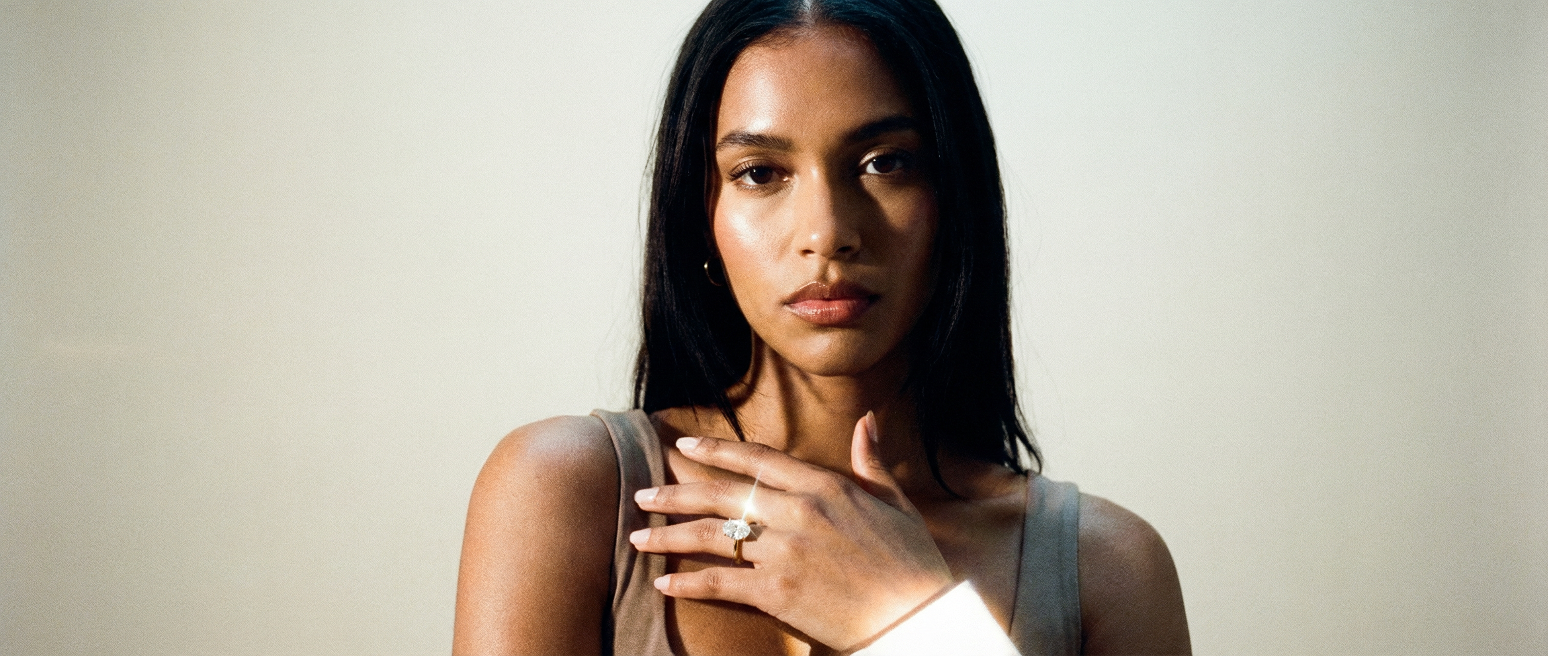 Woman wearing a ring on her finger against a plain background