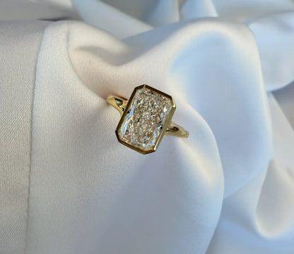 Gold ring with a diamond on a white fabric background