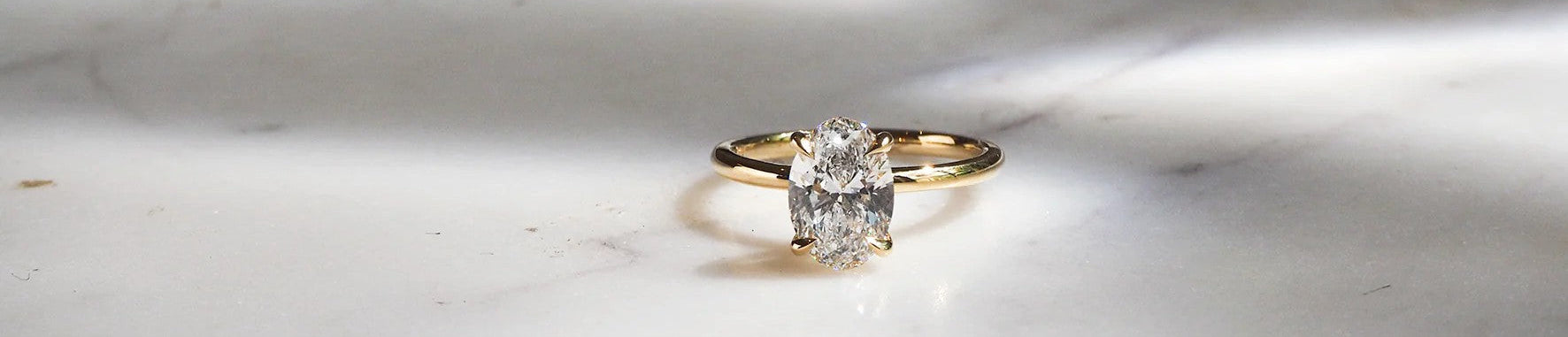 Gold ring with a diamond on a marble surface