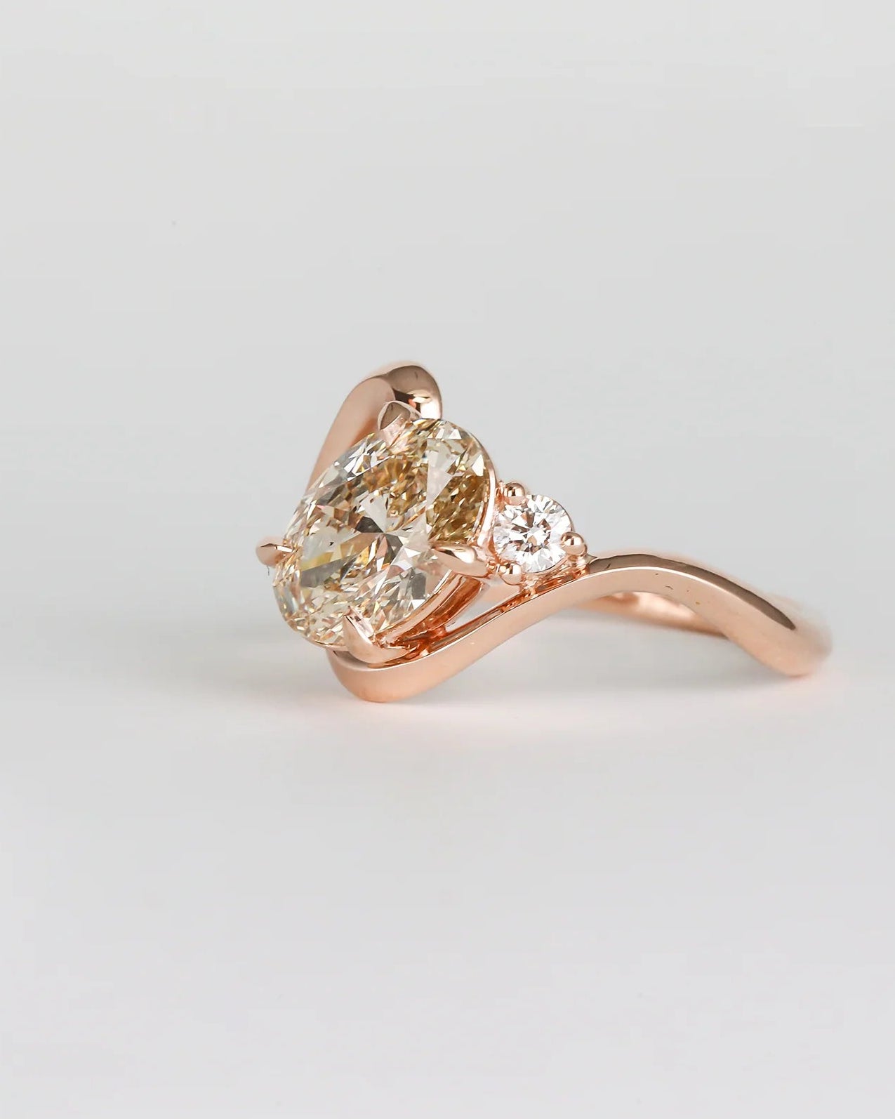 Rose gold ring with a pear-shaped diamond on a light gray background